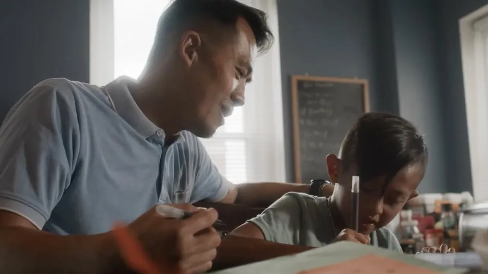 A dad helping his son with homework at the kitchen table